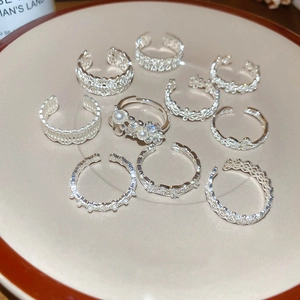 Detailed set of silver zircon rings with pearls and lace floral motifs on a white plate