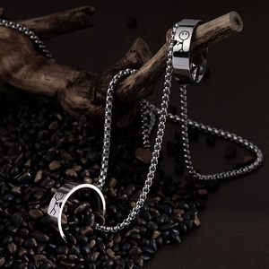 Gros plan du collier bague en acier inoxydable avec pendentif bonhomme sur bois et pierre