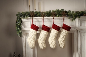 Classic red and off-white knitted Christmas stockings hanging on a fireplace mantel