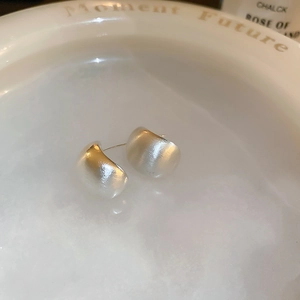 Macro shot of silver-colored brushed metal geometric earrings in a creative water setup
