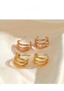 Detail view of gold and rose gold triple-layer C-shape earrings on silk background