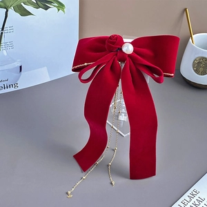 Detail of red velvet bow hair clip with handmade rose pearl and long bead tassels