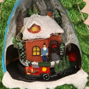 Macro detail of Christmas resin music box showing retro red train and snowy house with LED