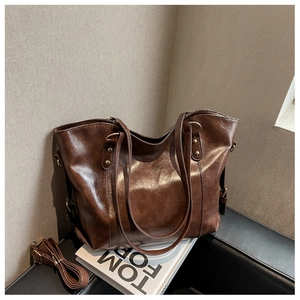Detailed view of a brown PU leather tote bag with a removable strap on a black chair