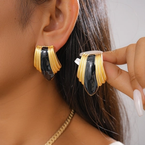 Macro detail of vintage gold shell earrings with black enamel center worn by model