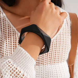 Detail of a minimalist black geometric resin bangle on model's wrist with polished finish