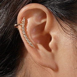 Close-up of gold ear cuff with zircons and pearls worn on the outer ear cartilage