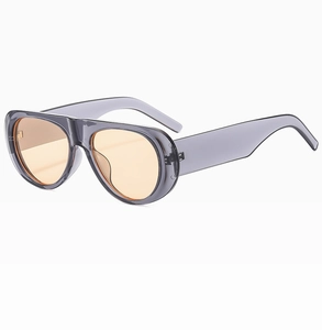 Detail view of transparent grey wide-leg sunglasses featuring warm amber tinted lenses