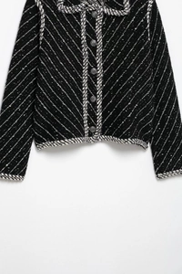 Close-up of black and white tweed jacket featuring woven trim and elegant buttons