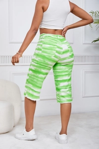 Detail of green and white tie-dye denim shorts featuring frayed edges and back pockets