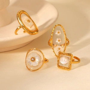 Detailed close-up of four gold-plated rings with white floral and shell inlay patterns