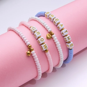 Détail de bracelets de perles avec étoiles dorées et lettres sur support rose