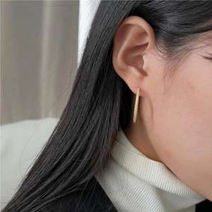 Close-up of elegant gold geometric bar earrings with pavé crystals on a model