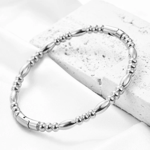 Macro detail of high-polish silver beaded bracelet featuring oval segments and secure clasp