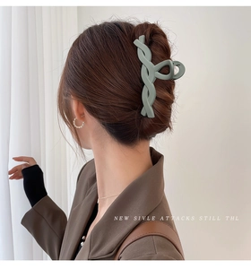 Detailed view of large sage green matte twisted hair claw clip on model hair