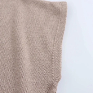 Detalle de la textura de punto beige y costuras laterales de alta calidad en la prenda