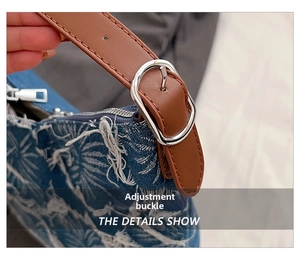 Detail of adjustable brown leather strap with silver metal buckle on denim tote bag