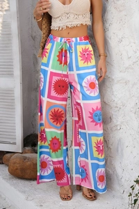 Détail d'un pantalon large bohème avec motifs soleil colorés et taille nouée sur un mannequin