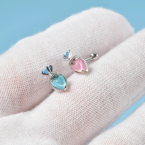 Detail of heart-shaped steel stud earrings with pink and blue zircons on white fabric
