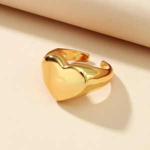 Macro close-up of polished gold heart-shaped open ring on a minimalist beige background