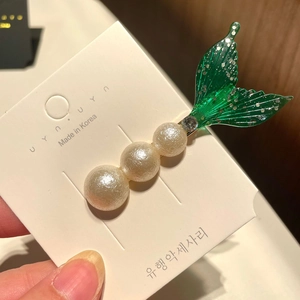 Detail of mermaid tail hair clip with white faux pearls and green glitter fin