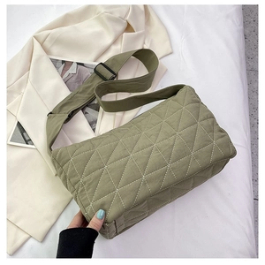 Detail of olive green quilted shoulder bag with white contrast stitching and wide strap
