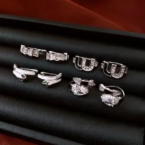 Collection of silver snake-shaped and zircon cuff earrings displayed on black leather box