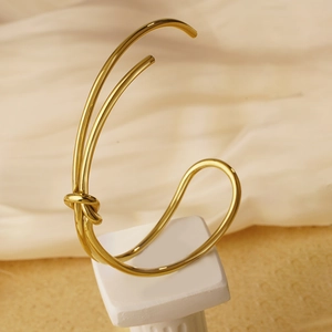 Minimalist 18K gold plated knotted open cuff bracelet for women on elegant pedestal