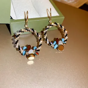 Boucles d'oreilles créoles dorées bohèmes avec pierres précieuses sur boîte verte