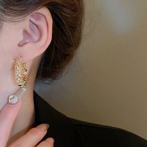 Gros plan d'une boucle d'oreille dorée en C avec texture argentée sur le mannequin