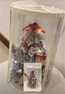 Close-up of Merry Christmas tree gift box with LOVE IS ETERNAL ribbon and LED lights