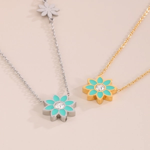 Détail de pendentifs fleurs en émail bleu avec pierre centrale sur chaînes dorées et argentées