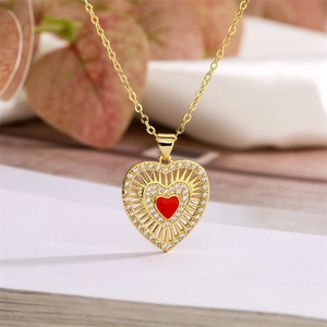 Close-up of golden heart pendant with pavé crystals and red enamel center on a chain