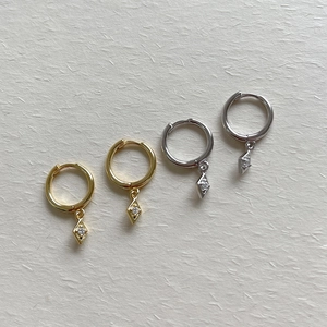 Detail of rhombic S925 sterling silver hoop earrings with zircon stones on fiber paper