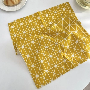 Détail d'un set de table en coton jaune avec un motif de grille géométrique blanche