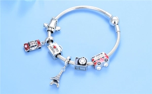Macro detail of S925 silver travel charms featuring a plane, bus, and Eiffel Tower pendant
