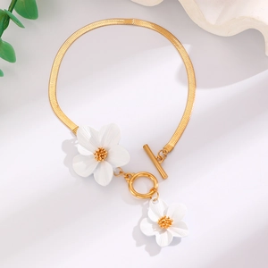 Detailed shot of golden snake chain bracelet with white flower pendants and OT clasp