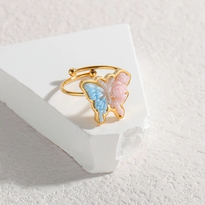 Macro detail of an 18k gold adjustable ring featuring a glittery blue and pink butterfly
