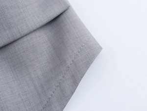 Vue détaillée de la texture du tissu tissé gris et des coutures soignées sur l'ensemble