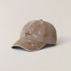 Brown washed vintage baseball cap with white splatter paint and X embroidery on the side