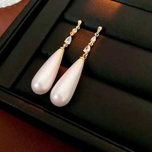 Macro detail of 14k gold plated pearl drop earrings with sparkling marquise zirconia stones