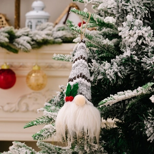 Christmas gnome ornament with grey knitted hat and white beard on snowy pine tree
