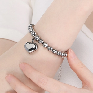 Detailed view of silver beaded bracelet with heart charm and extension chain on wrist