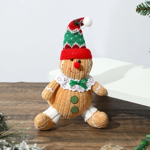 Close-up of a knitted gingerbread man doll with a red Christmas hat and green bow tie