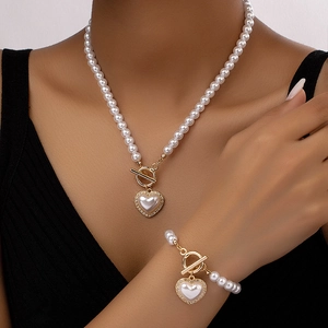 Close-up of pearl necklace and bracelet set with gold heart pendant and diamond accents