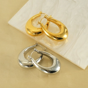 Polished 18K gold and silver U-shaped hoop earrings on a marble display stand