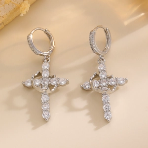 Detailed close-up of silver cross hoop earrings with shimmering white zircon stones