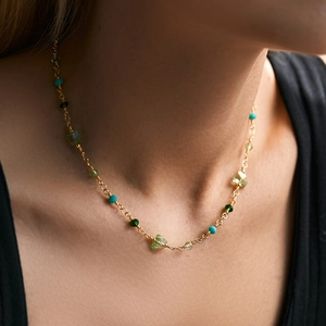 Detail view of handmade beaded necklace with green butterfly charm and gold chain