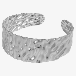 Macro detail of silver-tone wide cuff bracelet with textured hammered lava surface