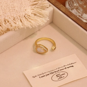 Detail shot of a pear-shaped white shell ring with 18K gold plating in a jewelry box